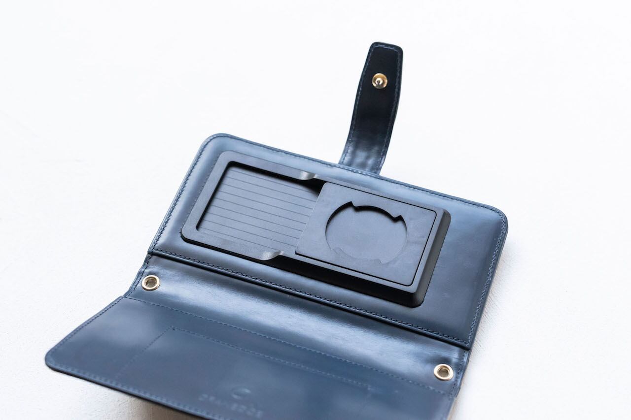内はつやのあるネイビーの牛革。蓋にはポケットが付いていてカードやお札がきれいに入り、お財布にも。