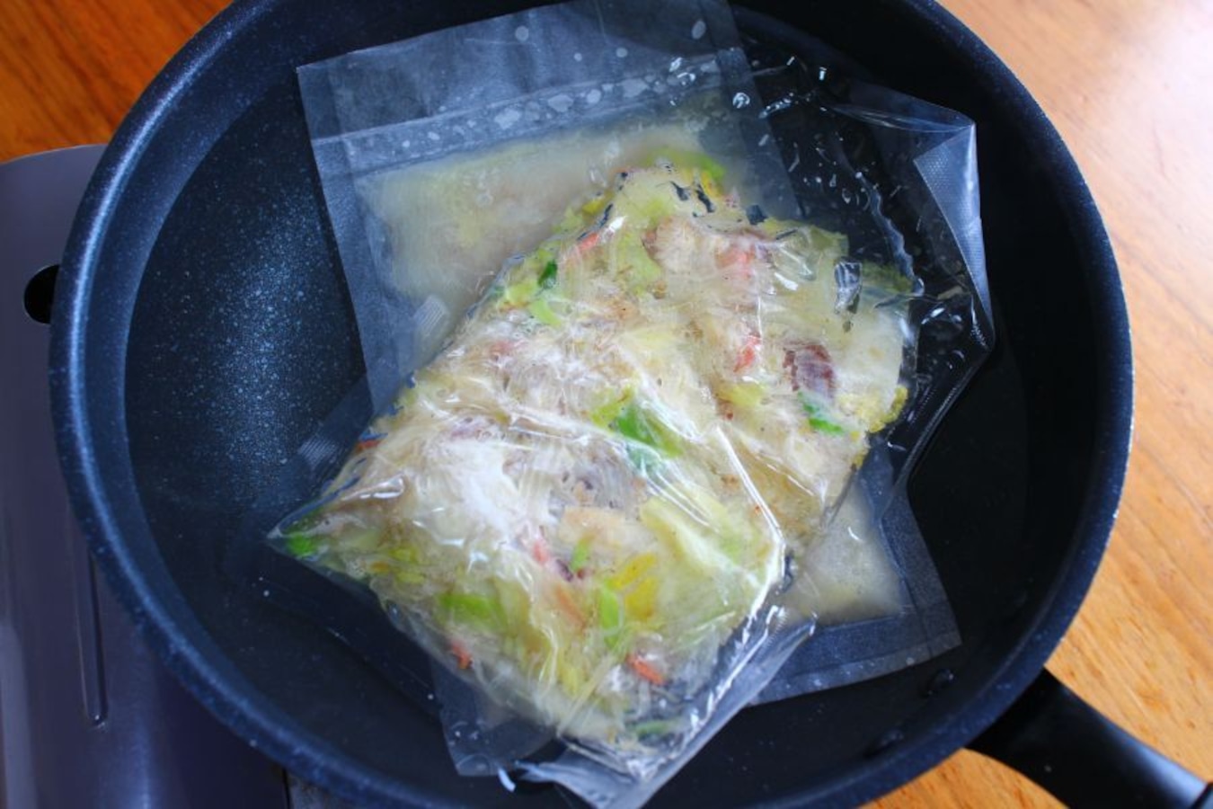 沸騰したお湯に、凍った袋のままスープと野菜を入れ３分ほど解凍する