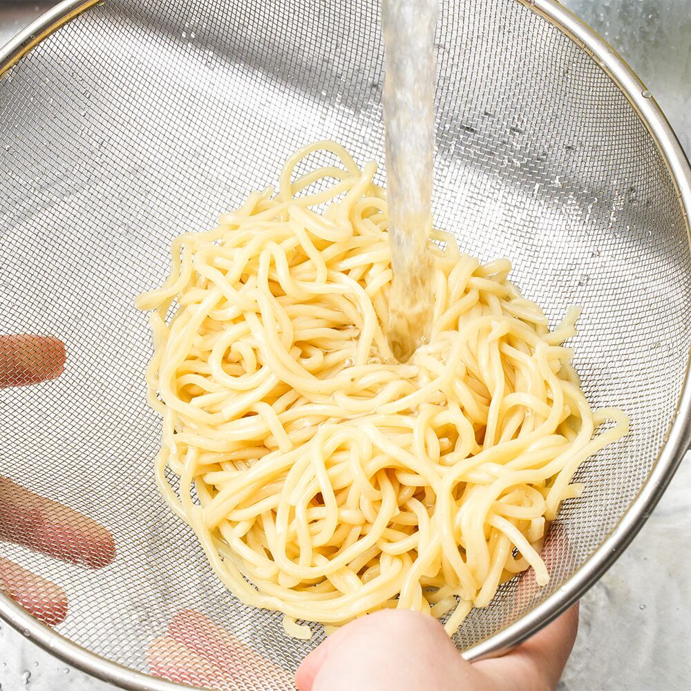 麺をザルに移し、流水で麺のヌメりをとる