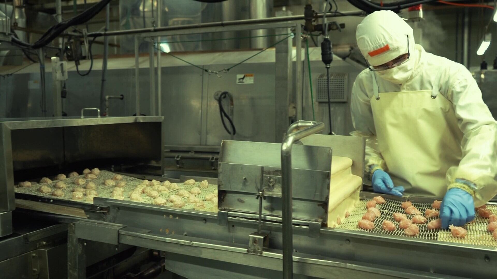 コンベアに乗って、揚げ油の中に落としていきます。2度揚げでカリッと揚げていきます。