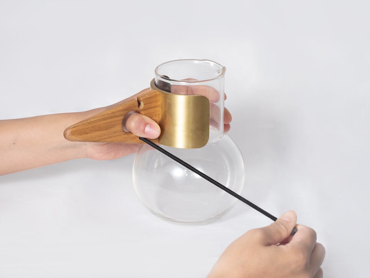 穴の部分に親指を入れて握り挟み、反対の手で紐をしっかり引っ張ります