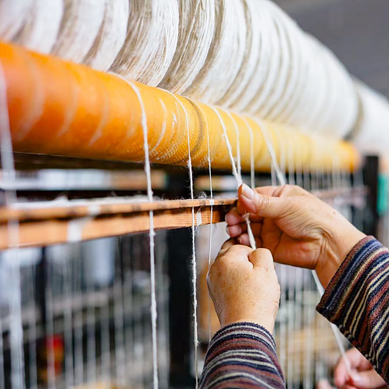 ワタを詰めた筒を回転させ上に向かってひきのばしながら糸を巻き取っていきます