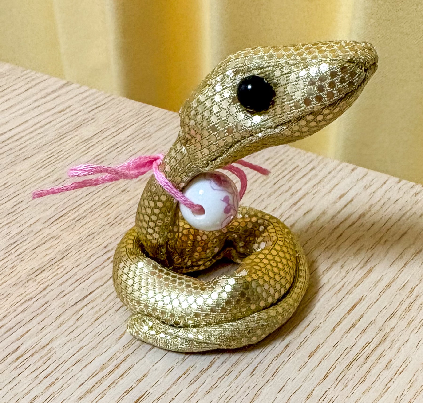 とんぼ玉を付けた金蛇のぬいぐるみ