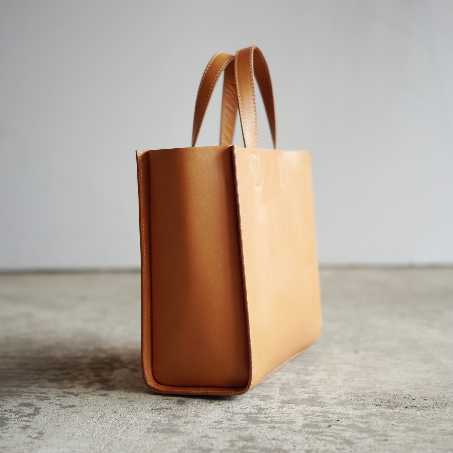 引き算の美学。ステッチが映えるレザーの手提げバッグ（ナチュラル