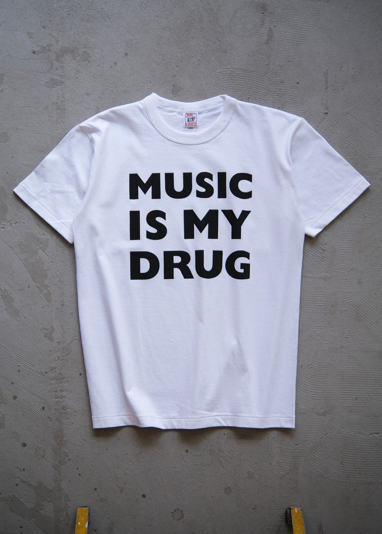 the "MUSIC IS MY DRUG" letterpress tee in white / black ink（受注生産）
