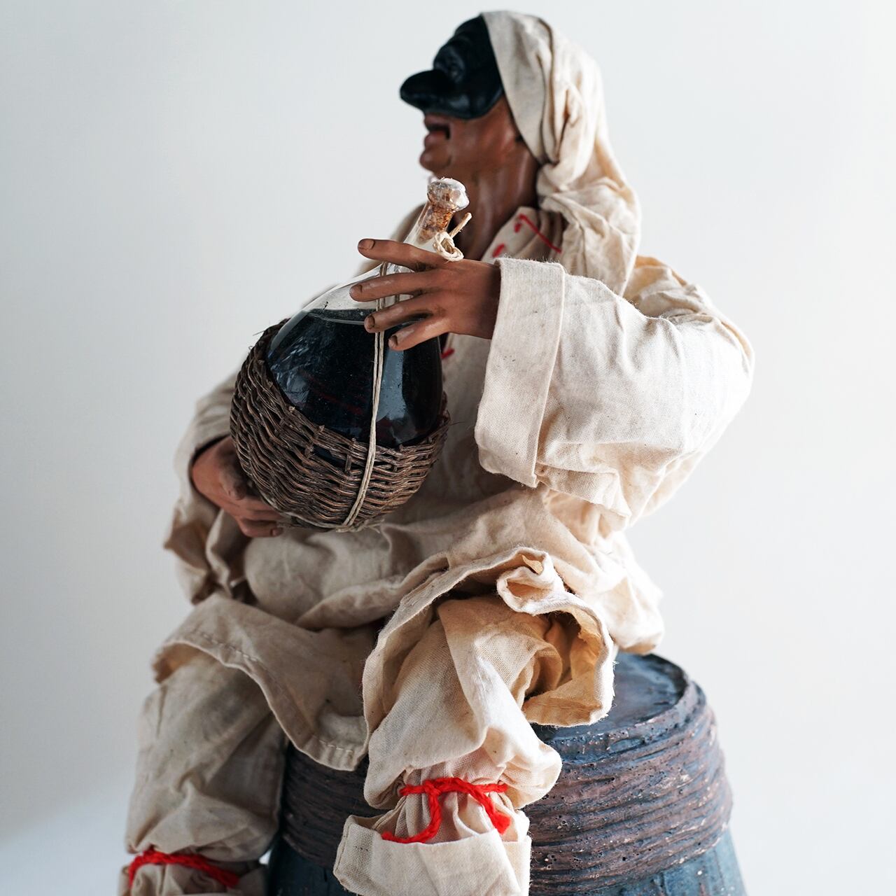 ナポリの幸運のお守り！フィアスコを持ってワイン樽に座るプルチネッラ