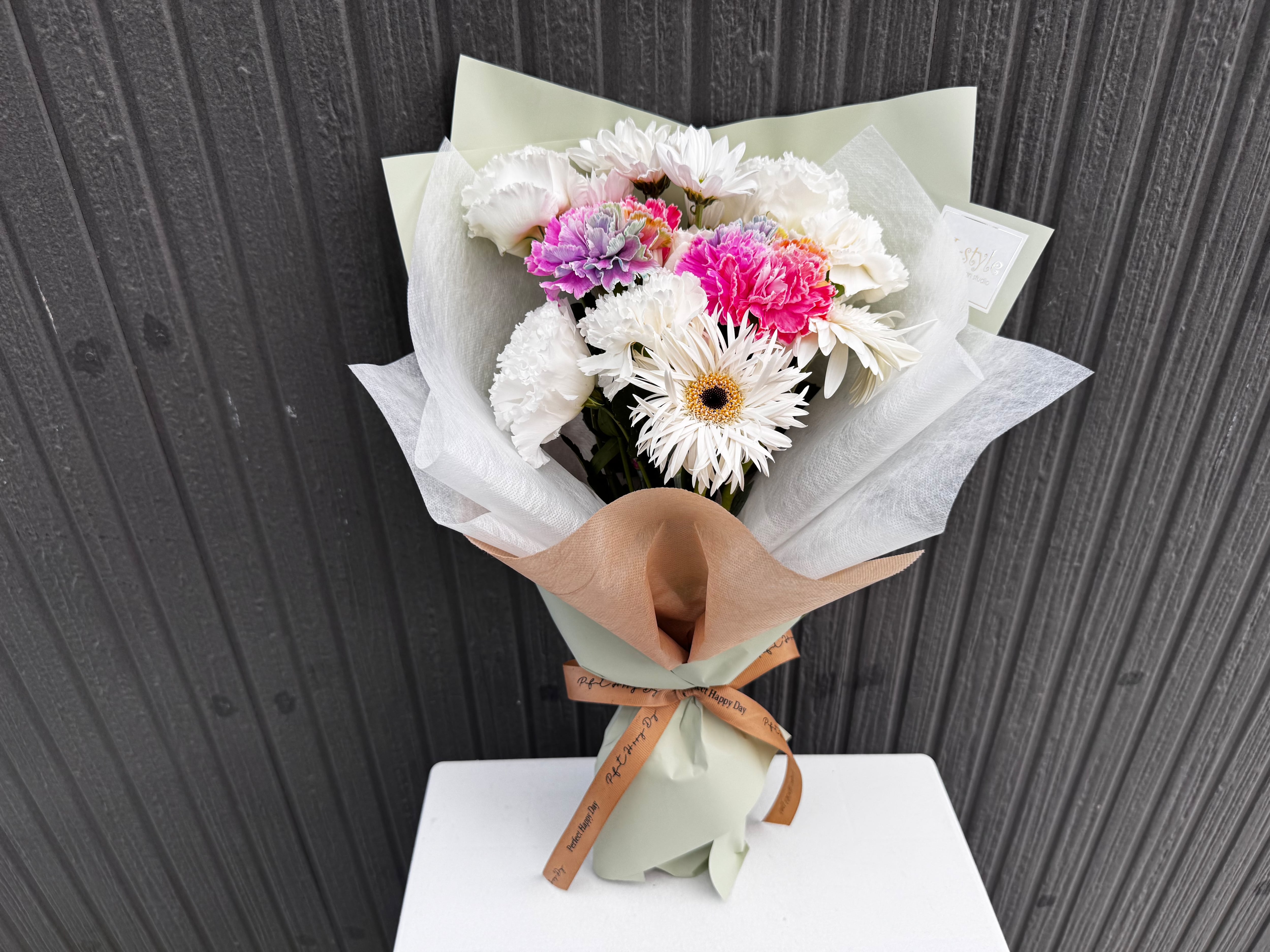 ホワイトに彩り添えるレインボーカーネーションの花束