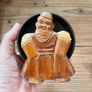 コースターを背負った木彫りのおじさん