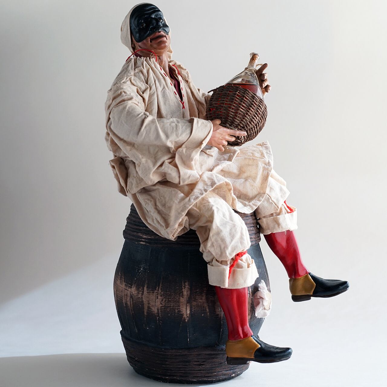 ナポリの幸運のお守り！フィアスコを持ってワイン樽に座るプルチネッラ