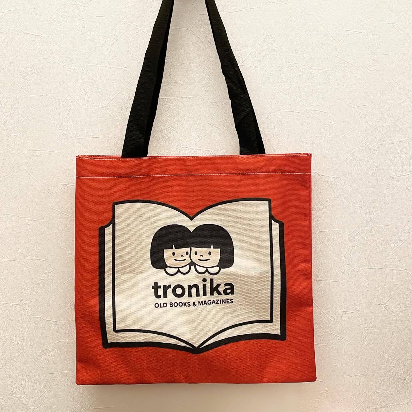 トートバッグ「トロニカ　双子イラスト　本のロゴマーク　背景赤　持ち手黒」 - 画像1