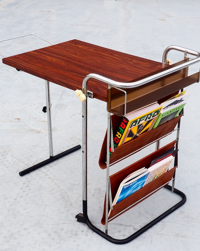 Table with foldable magazine rack, storage compartment, and towel rack