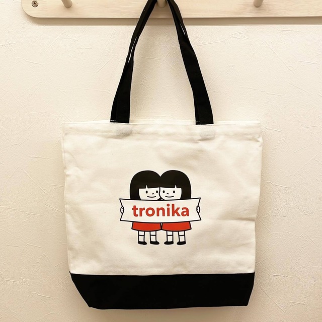 トートバッグ「トロニカ　双子イラスト　2人でロゴを持つ　白　持ち手黒　底黒」 - メイン画像