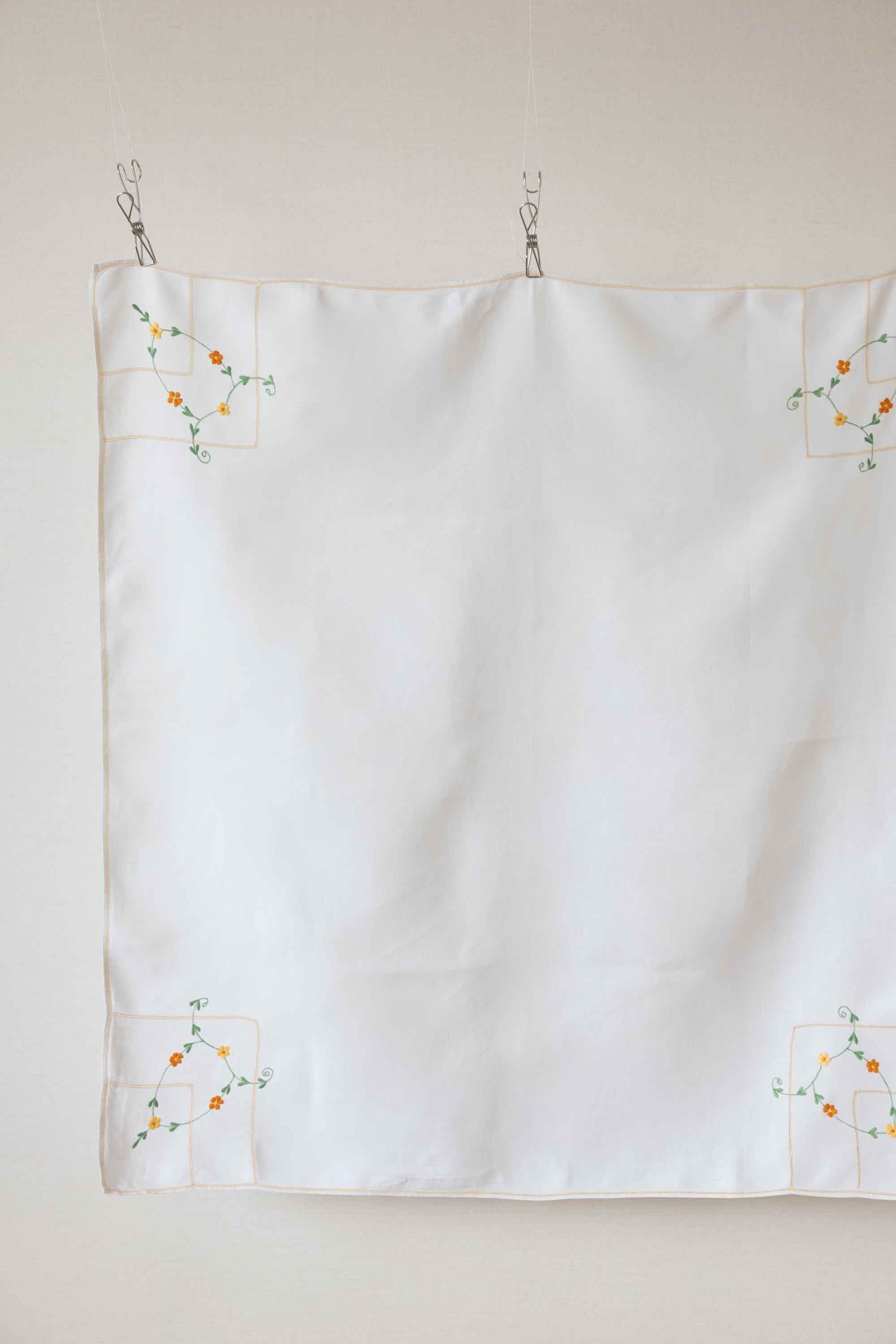 とろみのある麻生地に、オレンジやイエローの小花が機械刺繍で各コーナーに施されています。