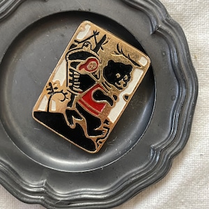 かごを背負ったクマのバッジ