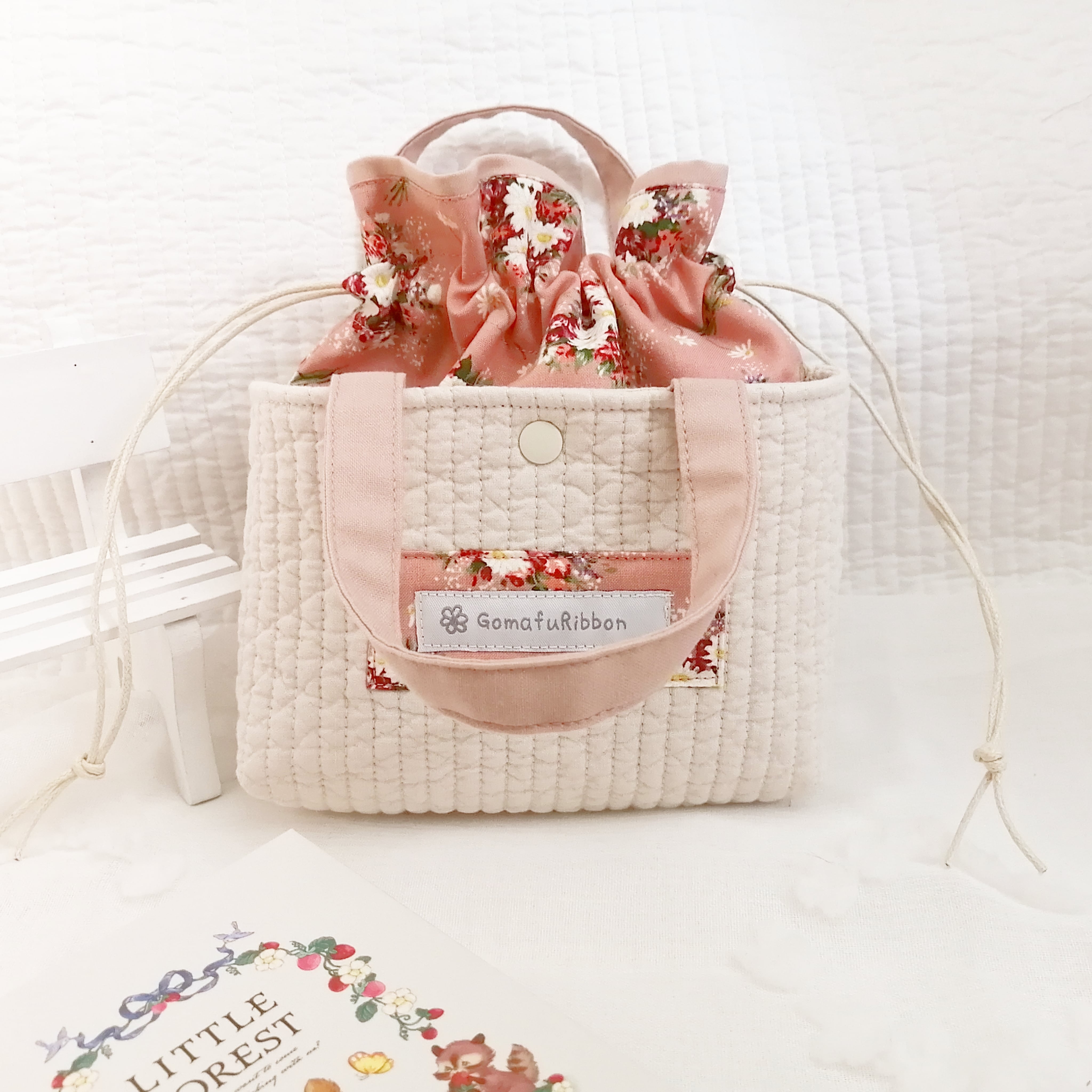 ヌビキルトのあおりポケット付き巾着ポーチ くすみピンク色の生地にマーガレットと赤いお花 グレーのギンガムチェック デザインタグ