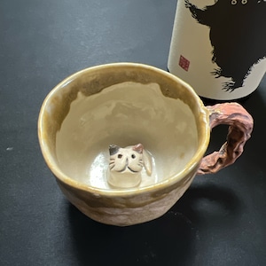 すねこすりが底から覗いてるマグカップ 妖怪陶器