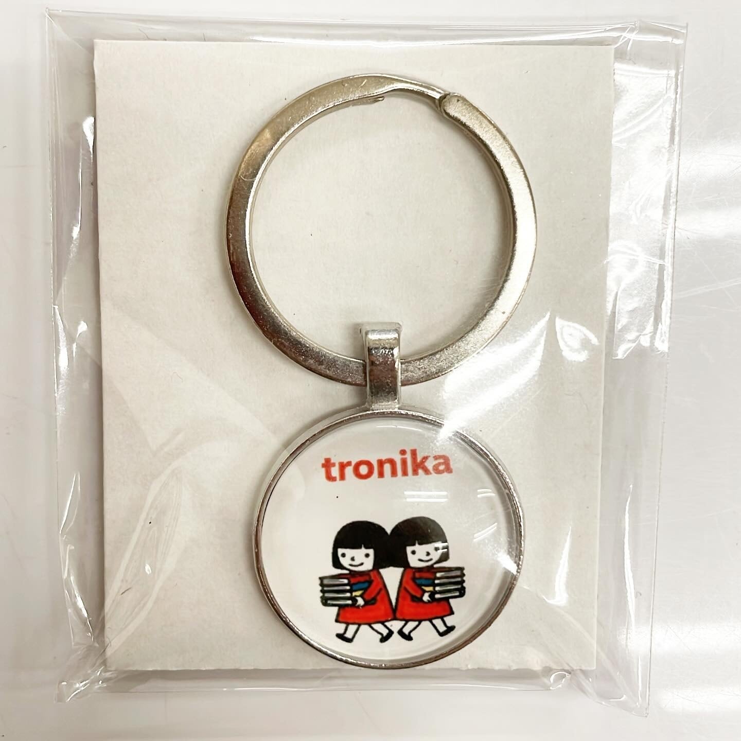 キーホルダー「トロニカ　双子　イラスト　本を運ぶ」 - 画像1
