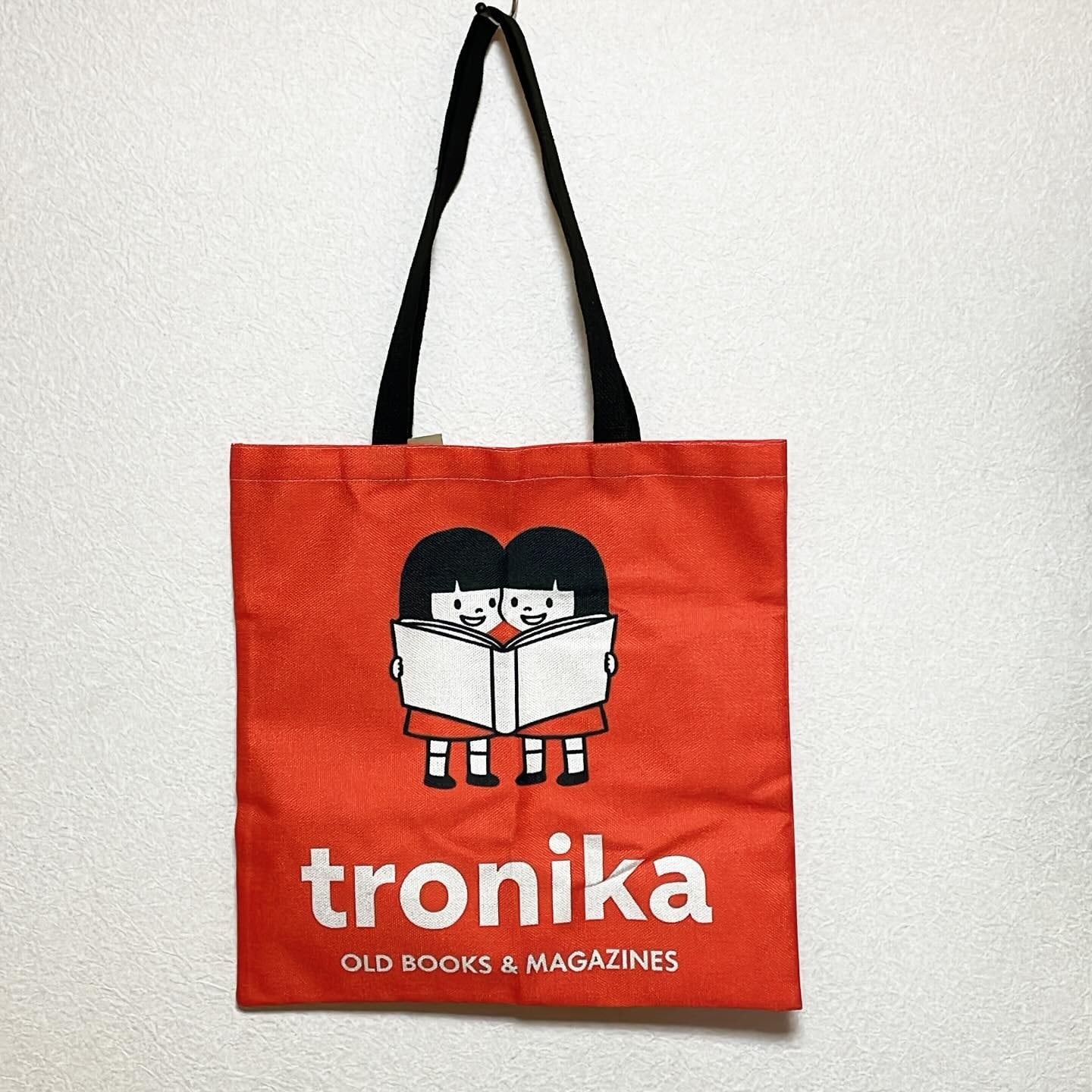 トートバッグ「トロニカ　双子　イラスト　一緒に大きい本を読む　背景赤」 - 画像1
