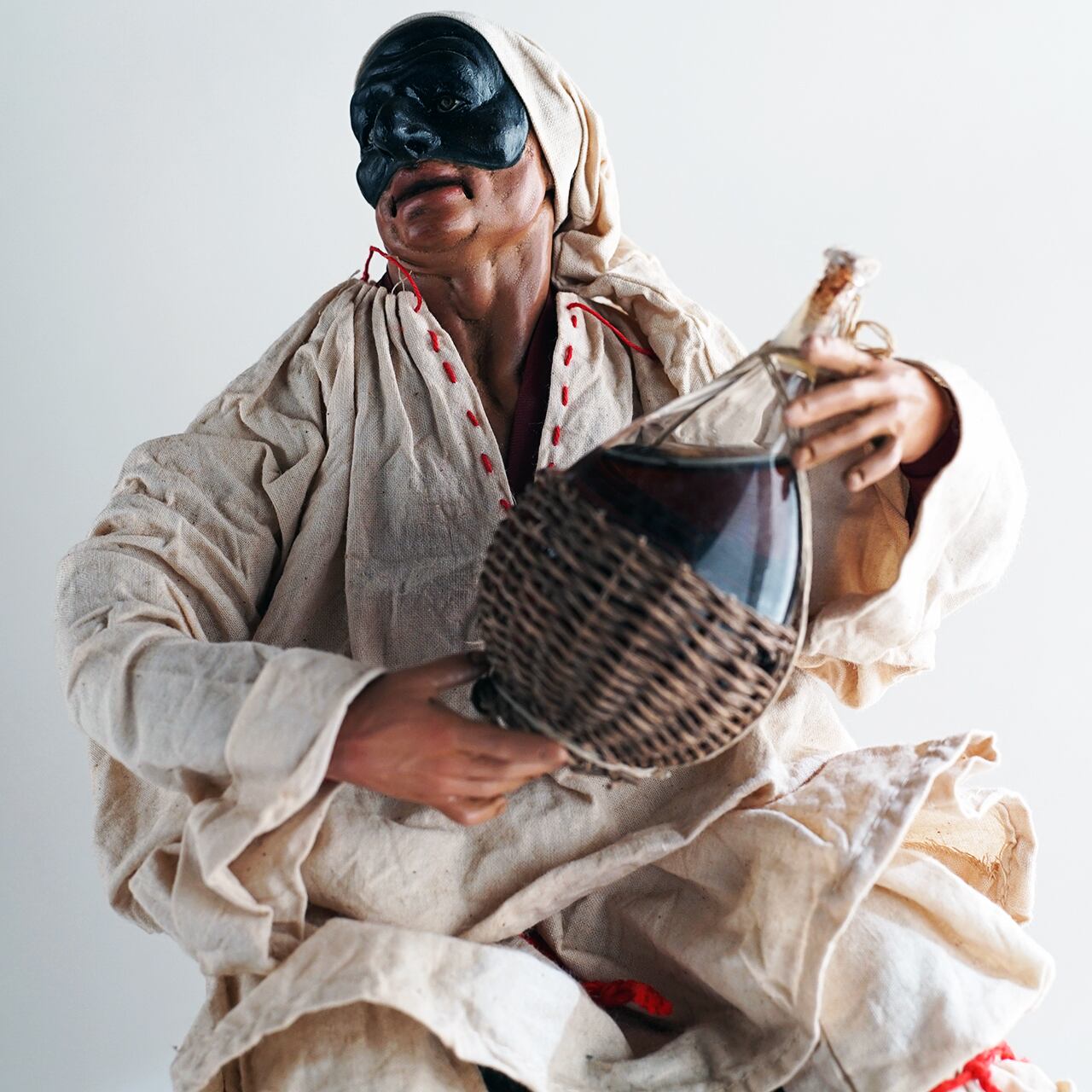 ナポリの幸運のお守り！フィアスコを持ってワイン樽に座るプルチネッラ