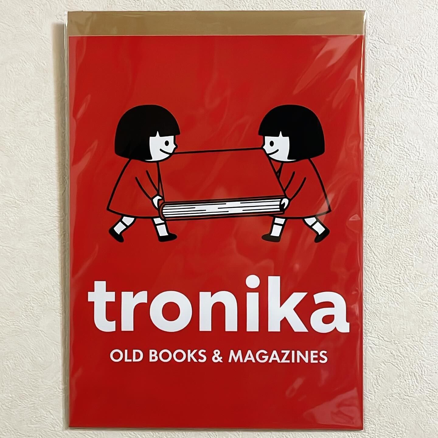 布 ポスター「トロニカ　双子　イラスト　大きな本を運ぶ　背景赤」 - 画像1