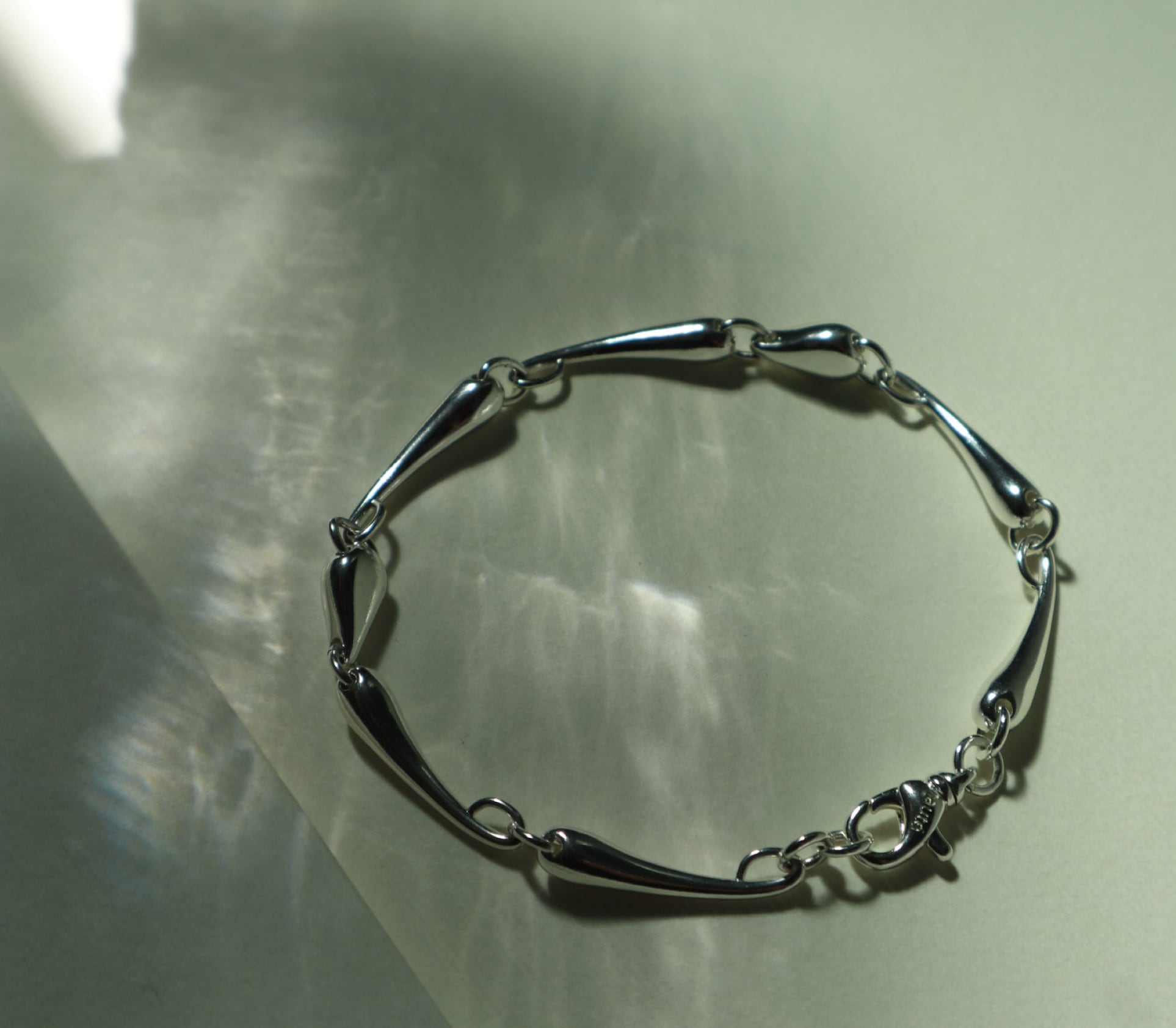 H Drop Bracelet “Veiné”

大地を巡る脈をテーマに実際に自然にある石からデザインインスピレーションを受けたされたブレスレット”Veiné”（ヴェーヌ）

連なるドロップ状のパーツは川の軌跡のように緩やかにカーブを描き、装いにさりげない立体感と上品な存在感を添えます。

コーディネートの仕上げとして、日常を静かに引き立てる一本です。
