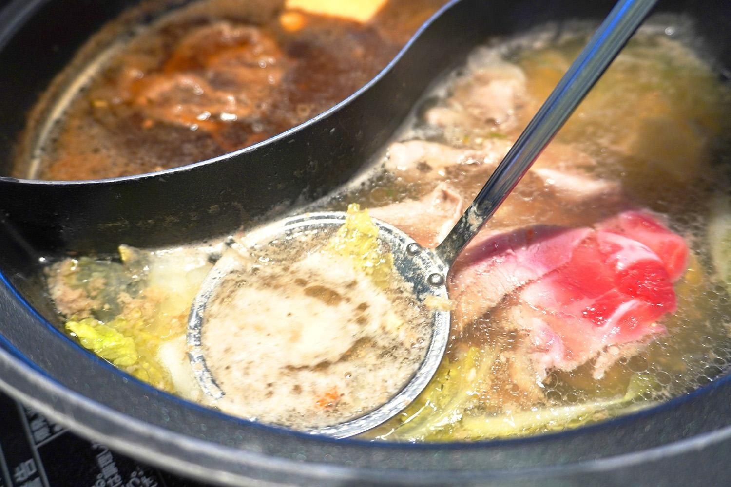 肉や野菜を煮た鍋に浮いたあくをあく取り網ですくい取っている様子