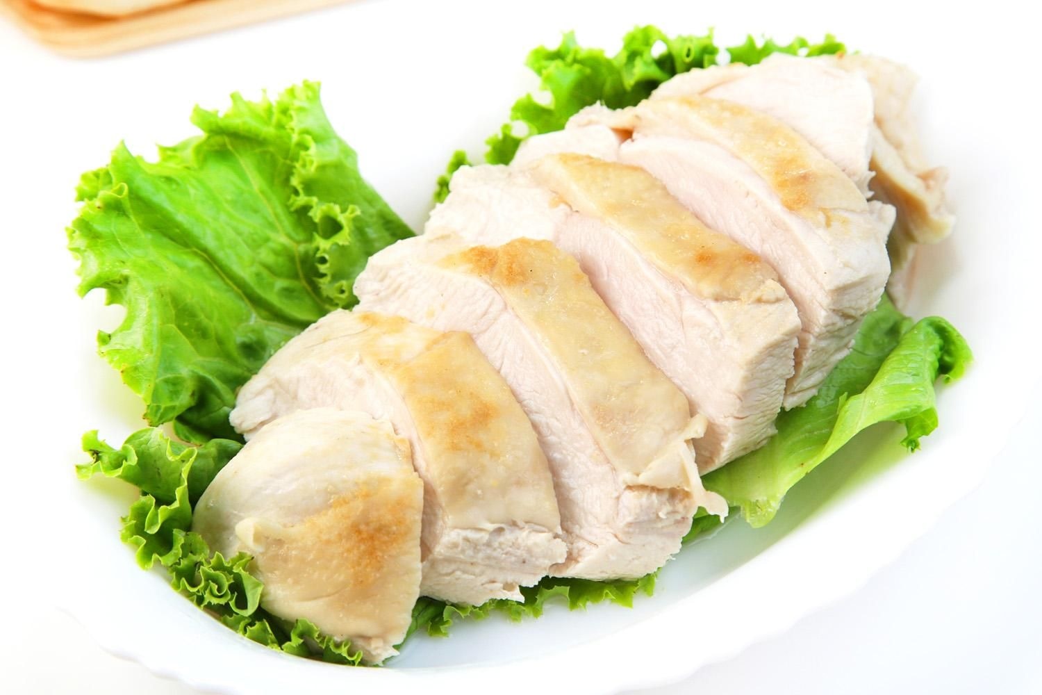 白い皿にレタスを敷いて盛り付けた、スライスした蒸し鶏（鶏むね肉）