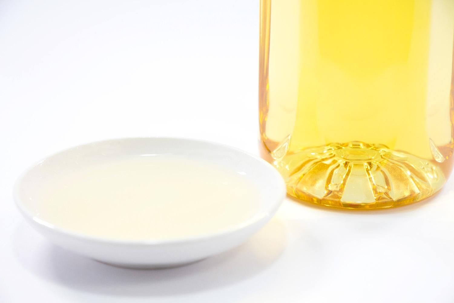 白い小皿に入った甘酒と、奥に置かれた琥珀色のみりんの瓶