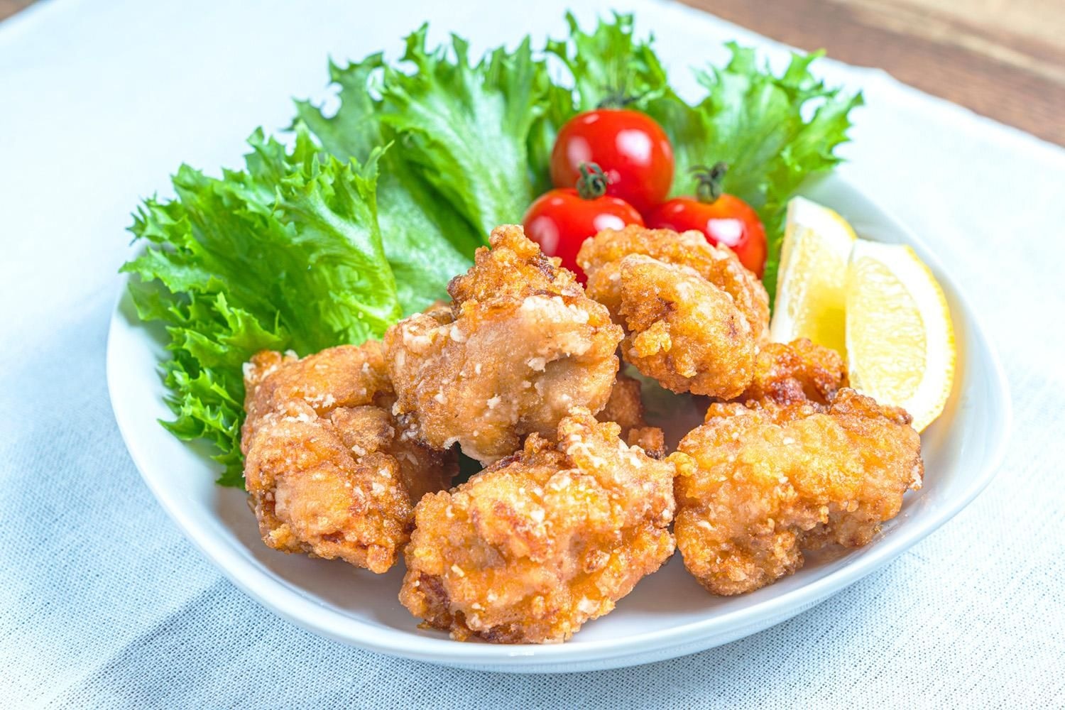 からあげの皿に、緑のレタス、赤いミニトマト、黄色のレモンをそえて彩りを足した一例