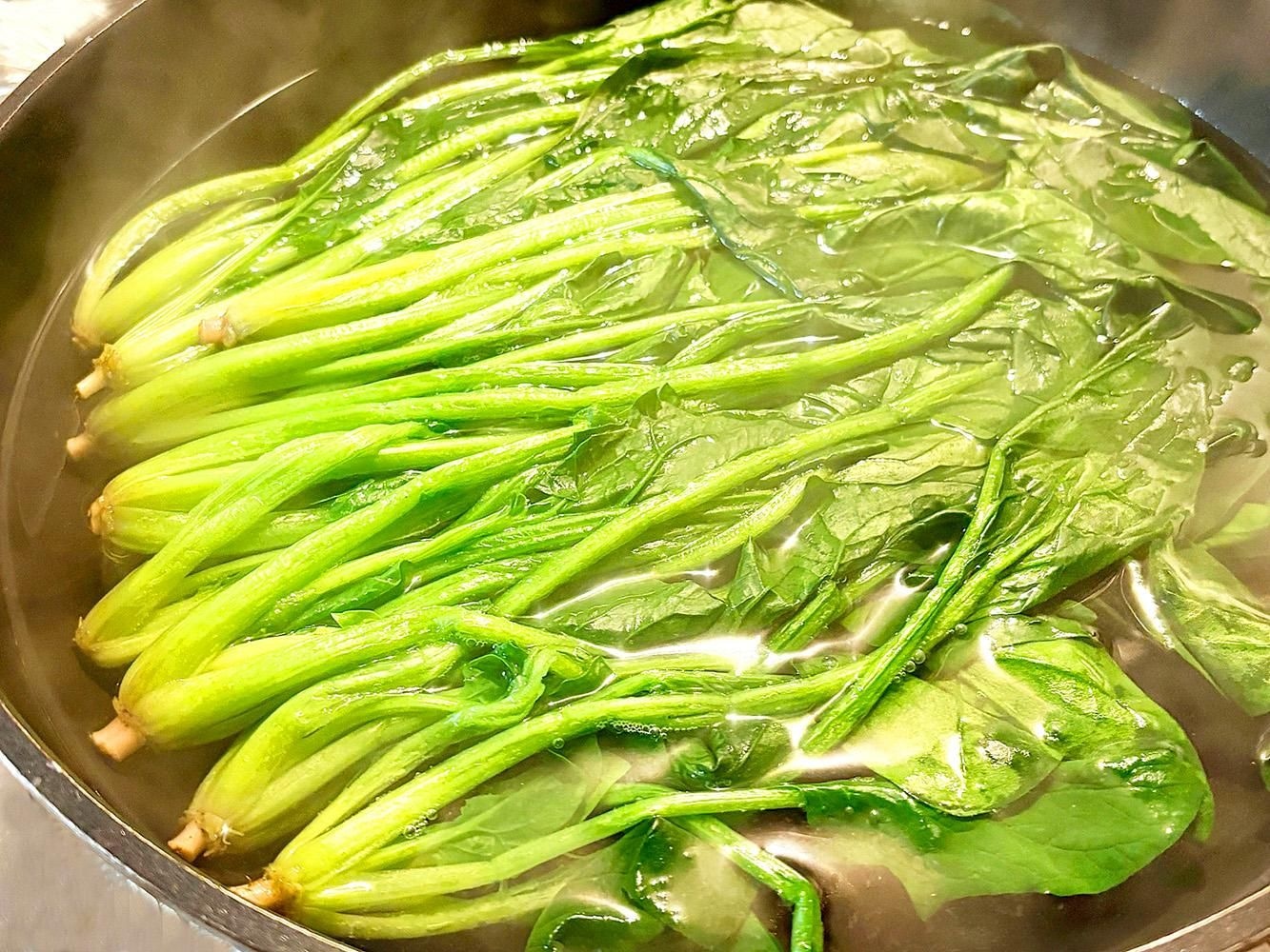 鍋に張った水にほうれん草を浸してあく抜きしている様子