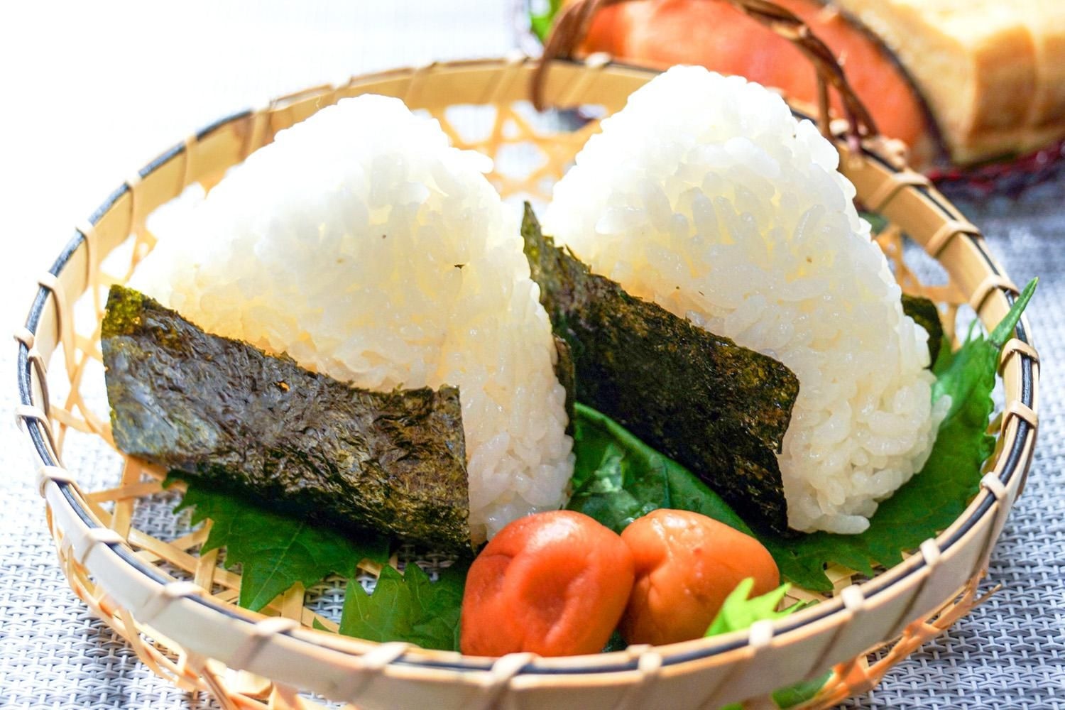 運動後の食事のイメージ。たんぱく質と糖質を含むおにぎり、ゆで卵、バナナ、牛乳、ヨーグルトが木製の盆に並ぶ